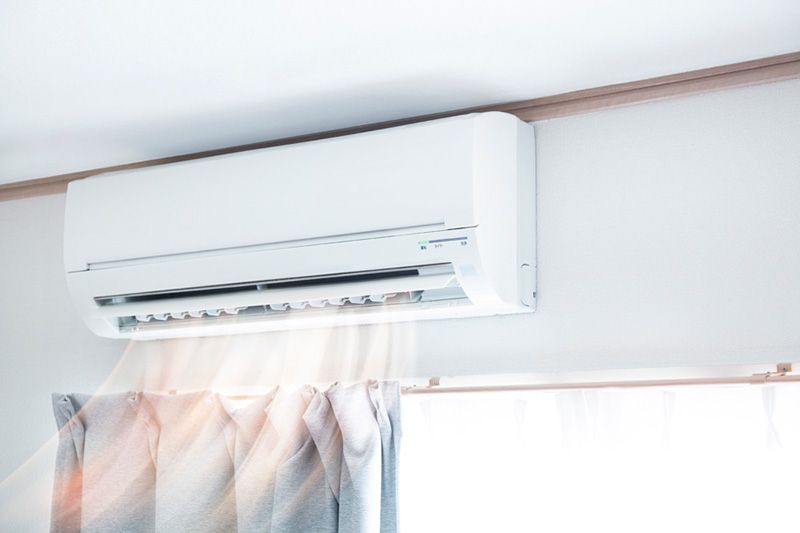 Ductless ACs Improve Indoor Air Quality and Control Humidity. Image depicts ductless system circulating cool air in all white room.