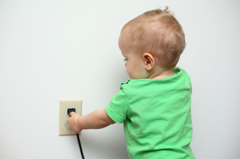 Toddler trying to unplug cord from home electrical system outlet. Ben’s Heating, AC & Electrical blog image.