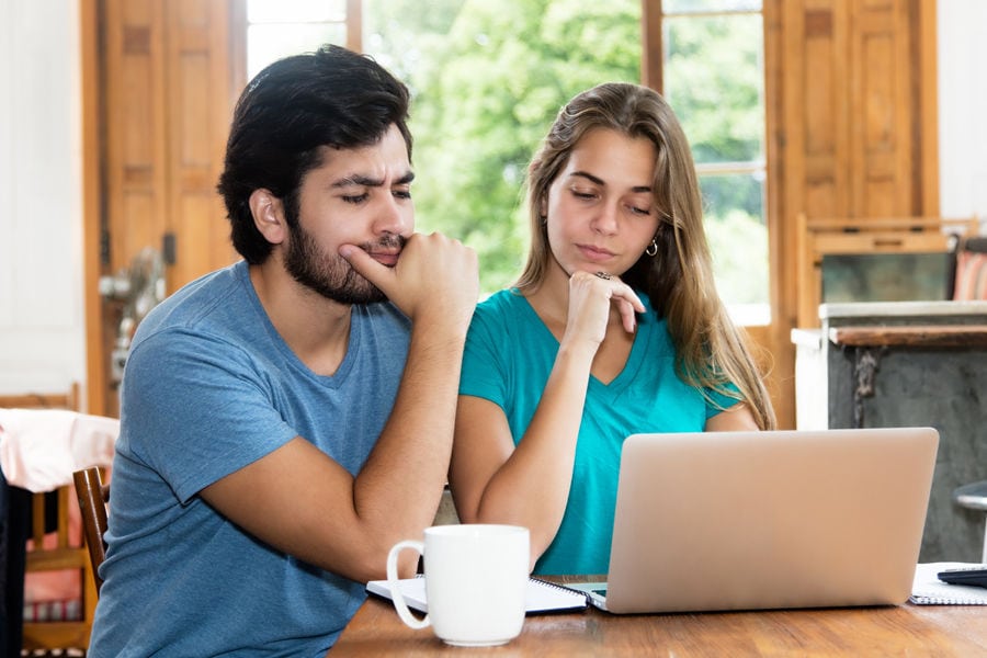 Couple puzzled at computer while researching heat pump. Ben's Heating & Air Conditioning blog image.