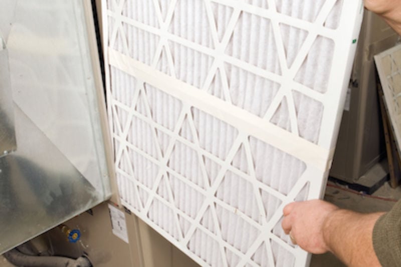 Person replacing furnace filter. Ben's Heating & Air Conditioning blog image.