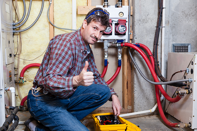 Image of what looks like a technician giving a thumbs up by a furnace. How Can I Make My Furnace Last Longer?